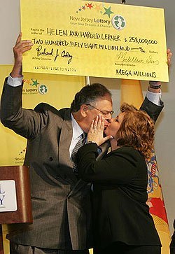 Harold Lerner gets a kiss from his wife Helen, as he holds up the Mega Millions lottery check, during a New Jersey Lottery Mega Millions News Conference at Seton Hall University in South Orange, N.J.